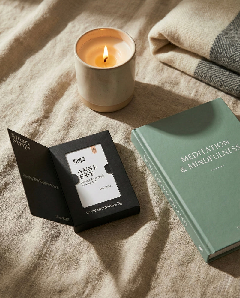 Candle burning on a textured surface with a book titled 'Meditation & Mindfulness' and a small black box.